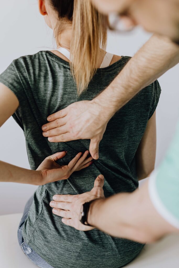 A person in a green shirt indicates lower back pain while another applies gentle pressure.