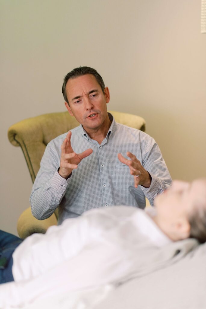 A man gestures while speaking to a person in a therapy session. Hypnotherapy.