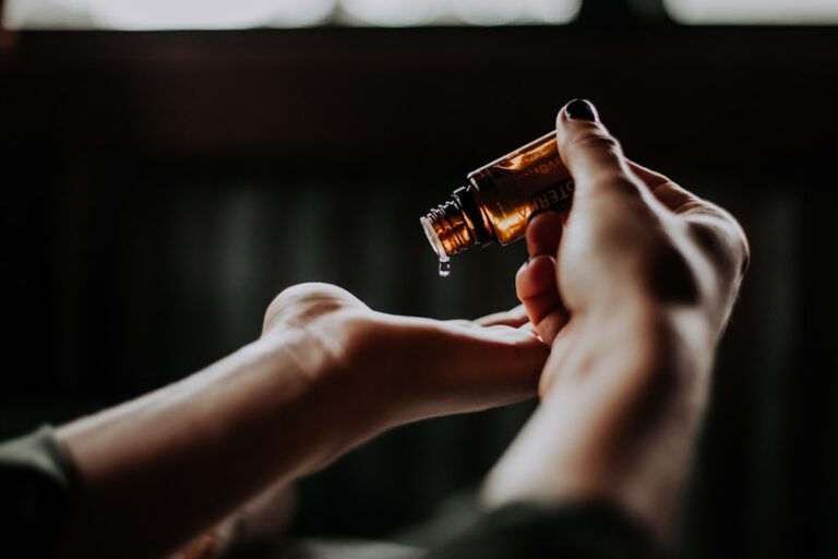 A person pours oil from an amber bottle onto their palm. Healthcare Professions.